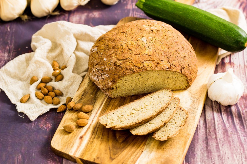 A wooden board with a loaf of zucchini bread, with slices of zucchini bread