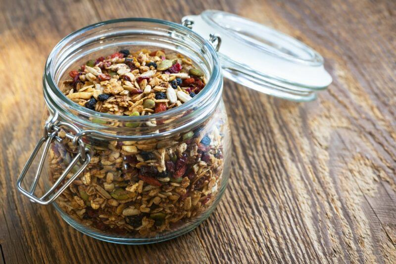 A wooden table with an open jar of granola