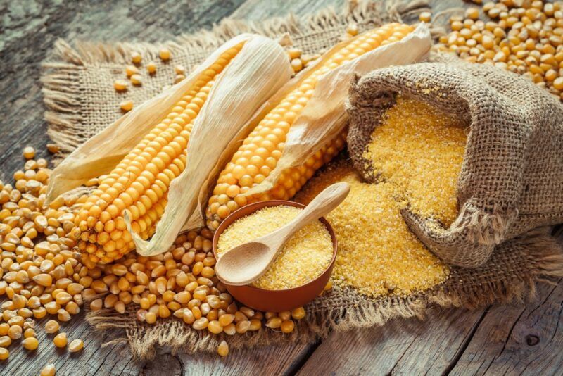 A wooden table with corn and corn related products, including polenta