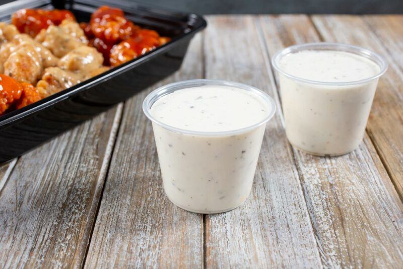 A wooden table with two small containers of ranch dressing