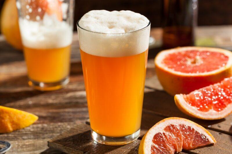 A wooden table with two glasses of sour beer, surrounded by grapefruit pieces. One of the glasses has been partly consumed