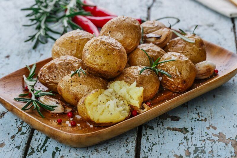 A wooden tray containing small baked potatoes