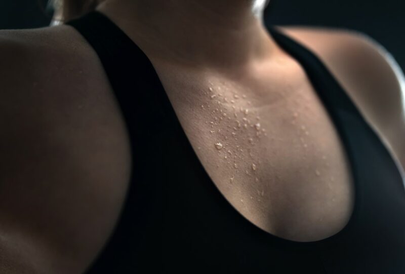 A young woman wearing a black bra, sweating from hot yoga