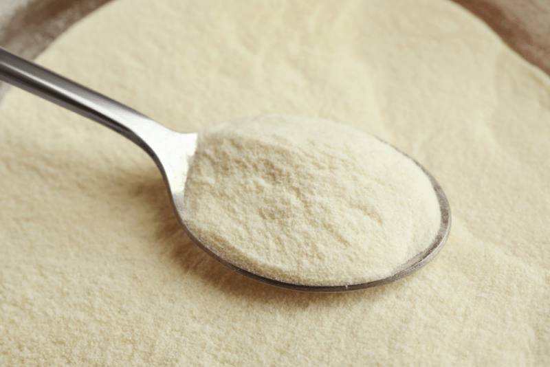 A large amount of agar agar powder in some type of container, with a metal spoon containing more of the powder resting on top.