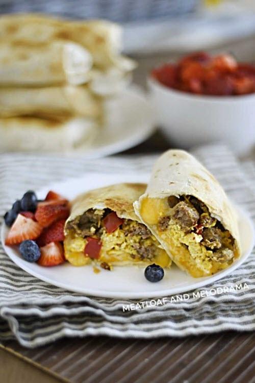 A white plate containing air fryer breakfast burritos plus fresh berries