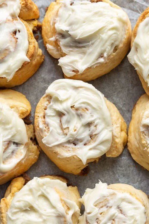 A collection of air fryer cinnamon rolls with frosting