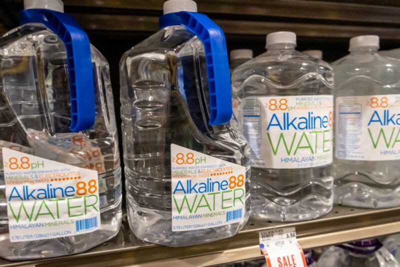 Two larger bottles of akaline water and two smaller ones in a grocery store