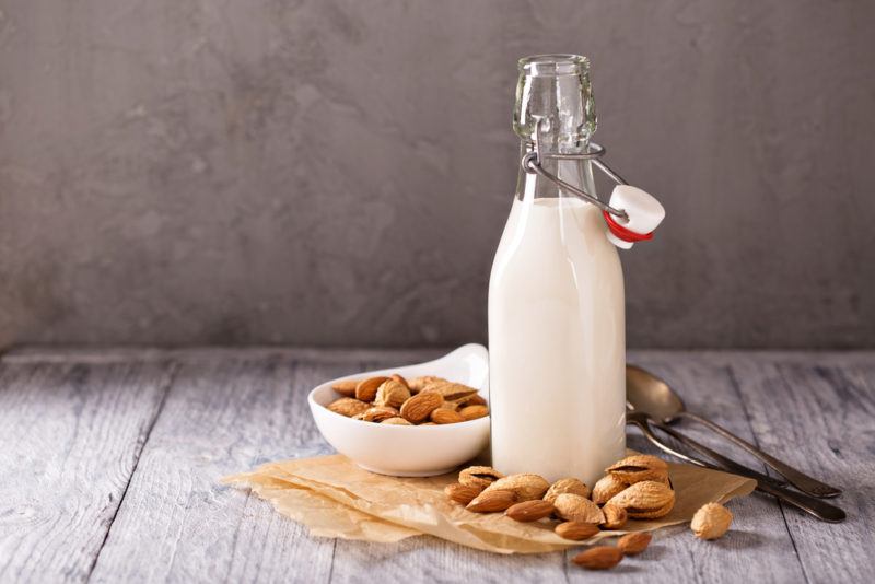 A bottle of almond milk next to a bowl of almonds