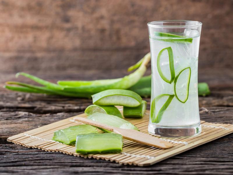 A glass of water with sliced aloe on a table