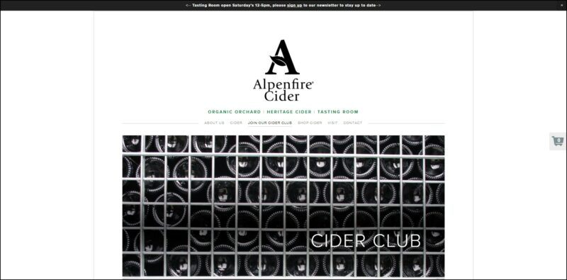 screenshot of Alpenfire Cider Club's web page, a dominantly white page with black announcement bar on top followed by the website's logo/name and the main menu underneath, the page is showing a large closeup image of bottles of cider.