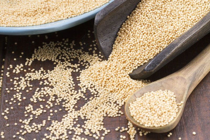 Grains of amaranth spilling from a scoop and a spoon