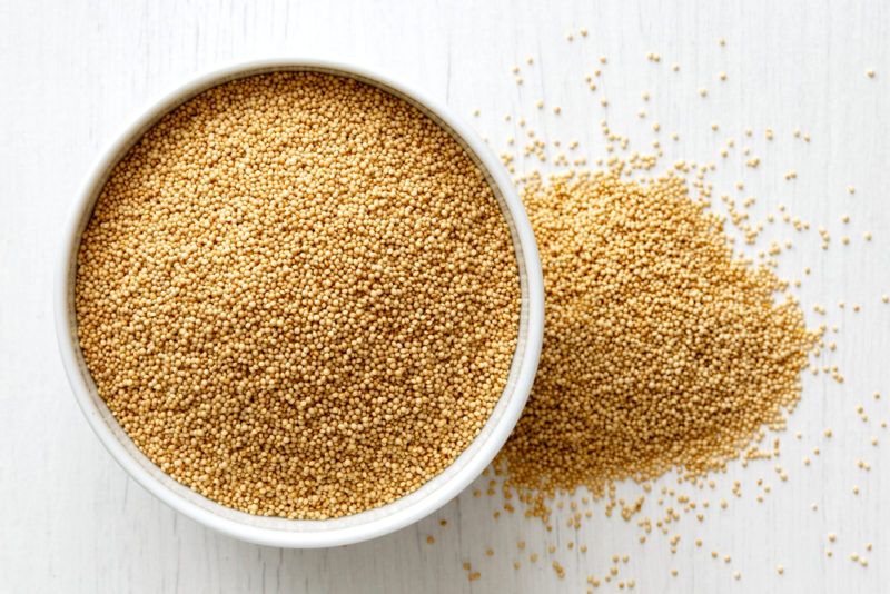 A white bowl containing amaranth with some spilling onto the table