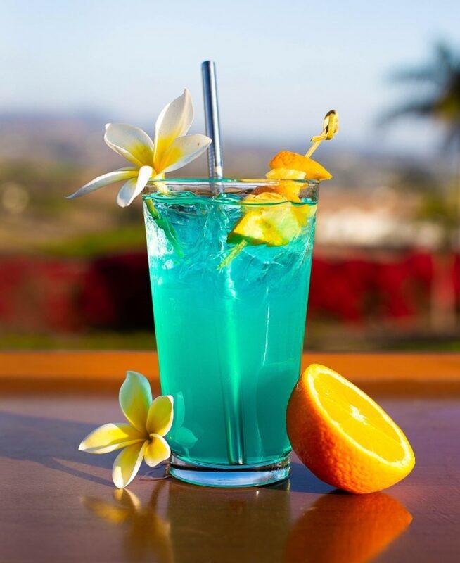 A tall glass containing a bright blue AMF cocktail