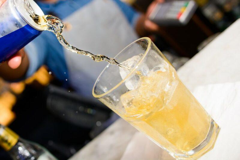 Red Bull being poured from a can into a glass, to be used in an F-bomb cocktail