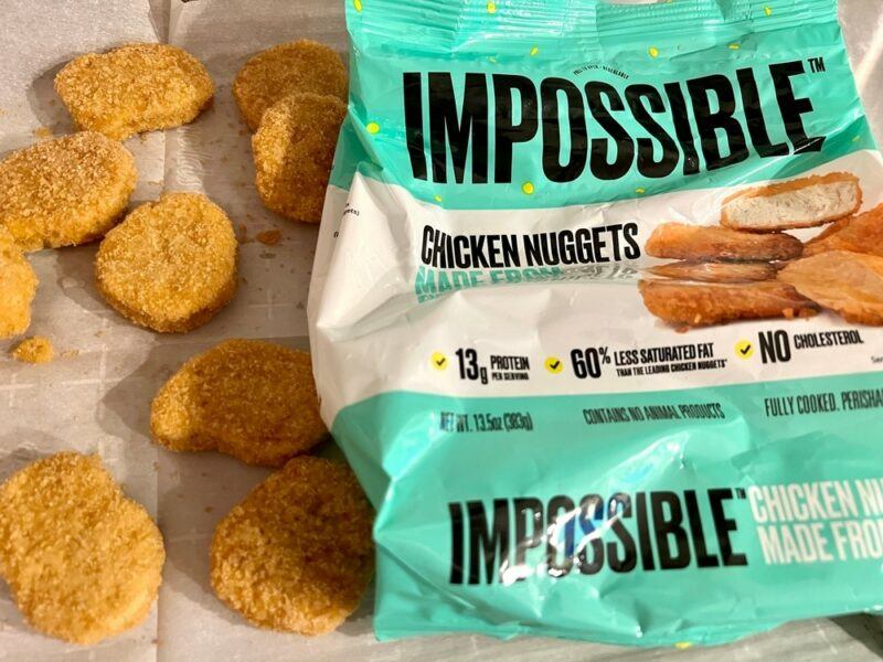 A bag of Impossible Chicken nuggets, next to some of the chicken nuggets on a table