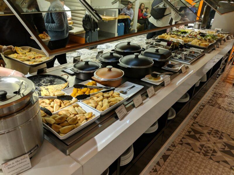 An airport buffet with many meals, including many covered dishes