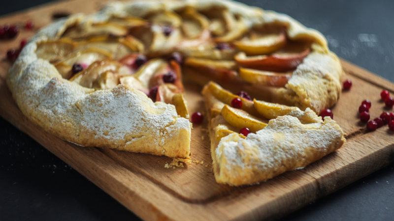 An apple and cranberry tart on a wooden board