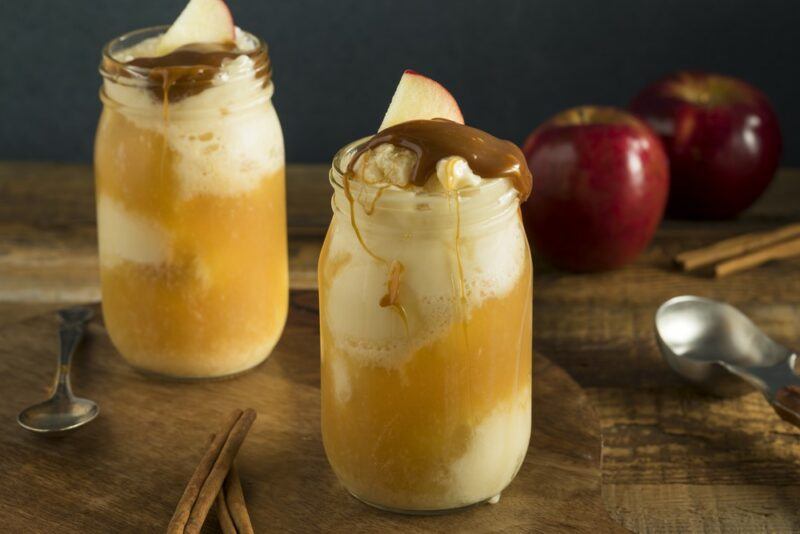 Two mason jars containing an eggnog ice cream float, tipped with ice cream and chocolate sauce