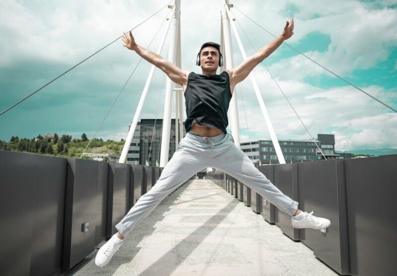 An excited man outside doing star jumps