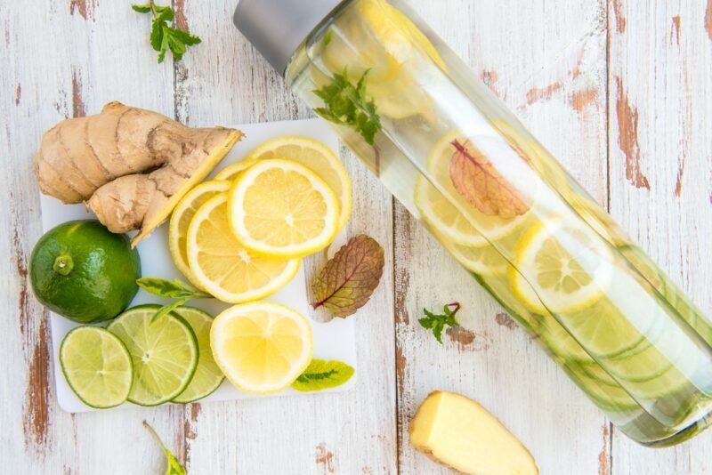 Lemon water made in an infuser bottle, with more lemons and limes sliced next to it.