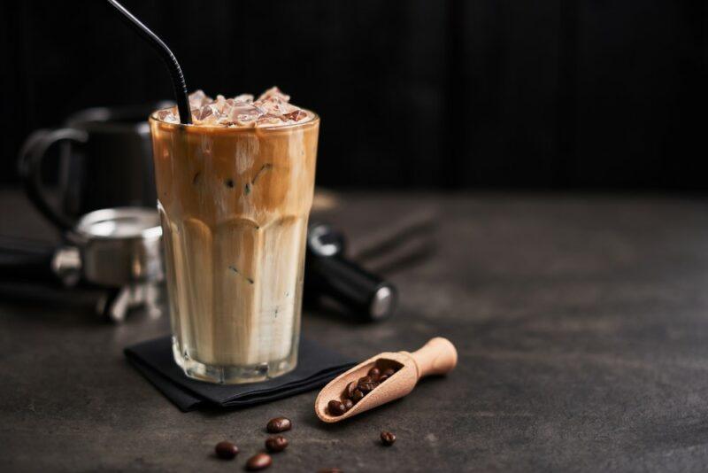 An oat and honey cocktail in a tall glass, next to various tools for making coffee