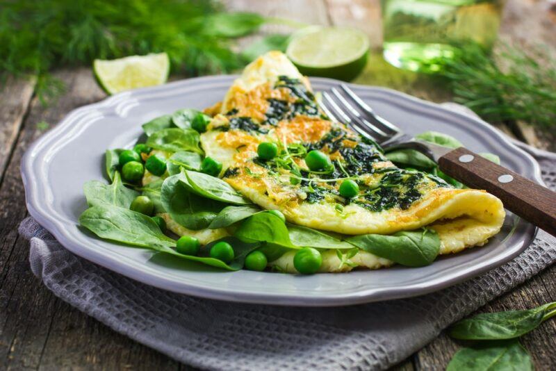 A gray plate with a green pea omelet and a fork