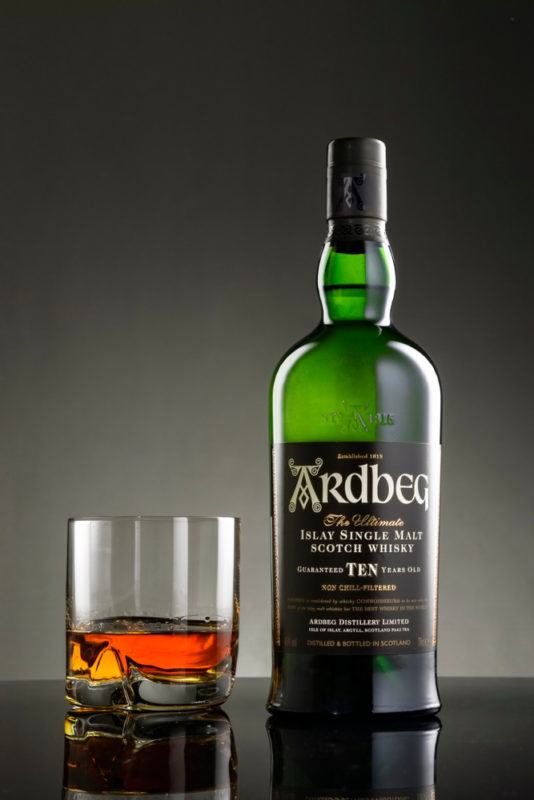 Ardbeg ten bottle with scotch glass and caramel colored whisky