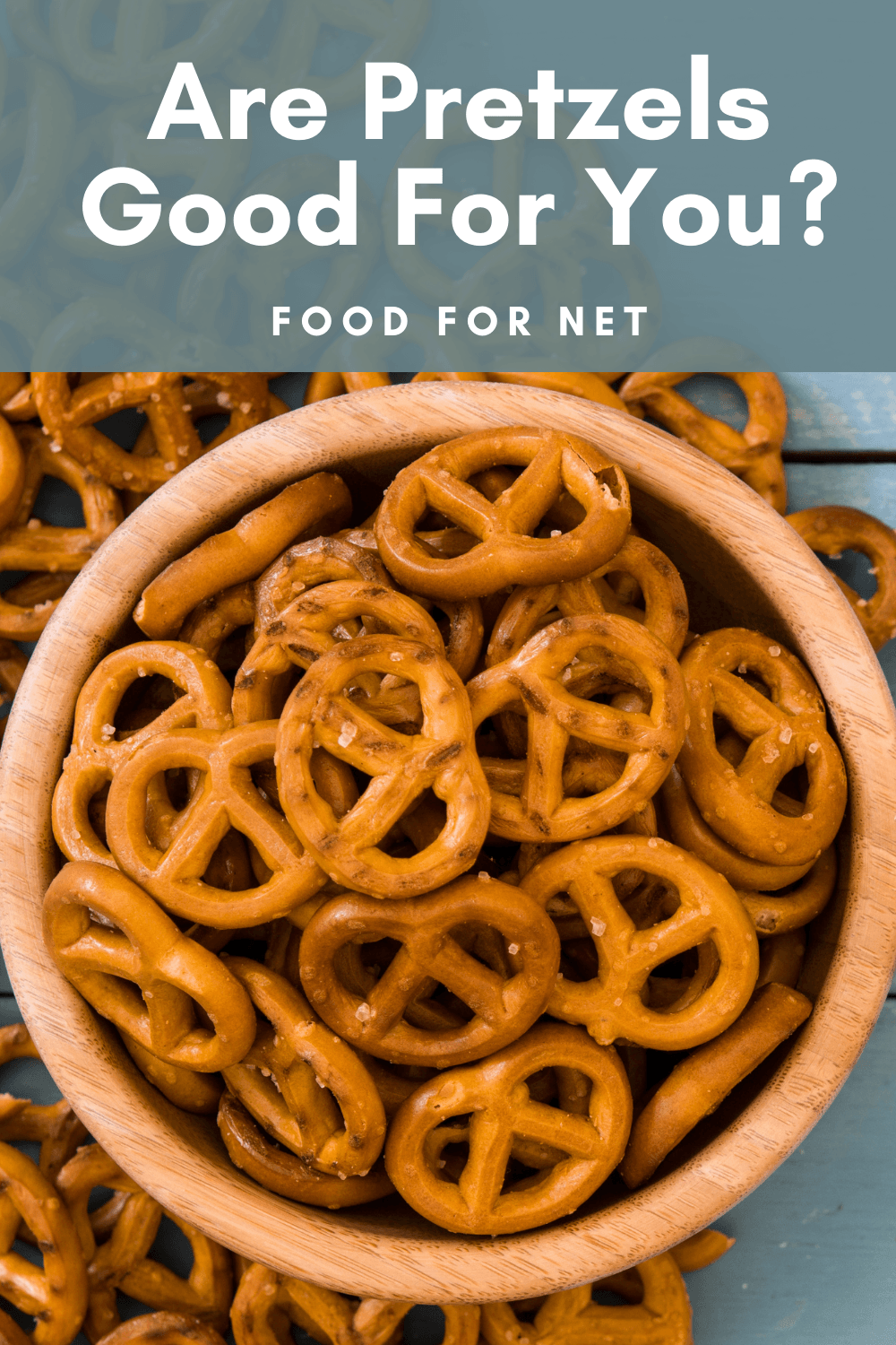 A wooden bowl with salted pretzels, with a few more scattered on the table, looking at whether pretzels are good for you