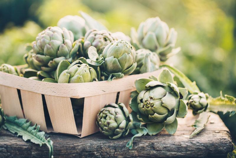 A basket of artichokes on a table outside