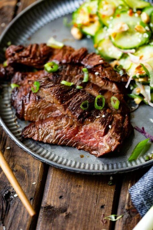 A grey dish with sliced steak that has been cooked in marinade