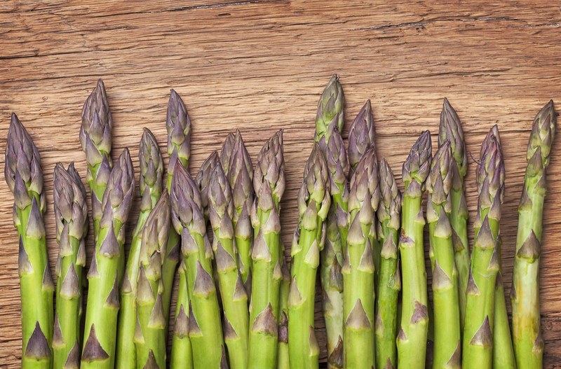 This photo shows a row of asparagus on a wooden cutting board.