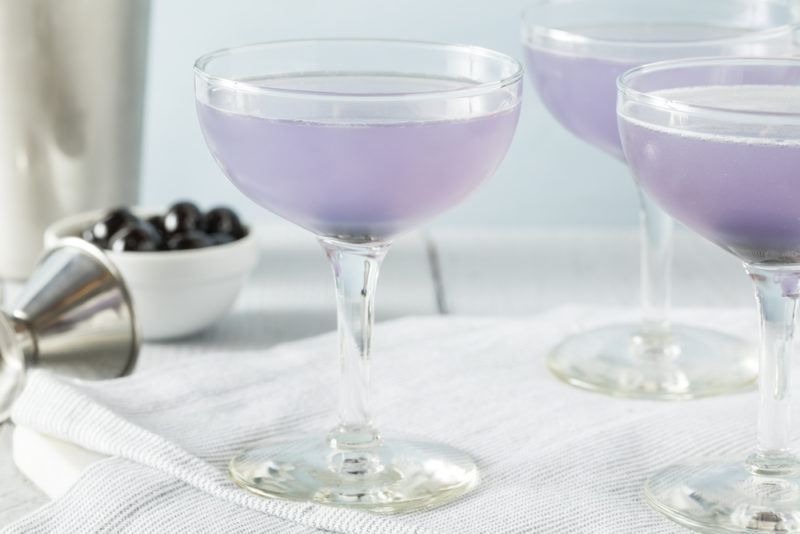 Three glasses of an aviation cocktail with their light purple coloring