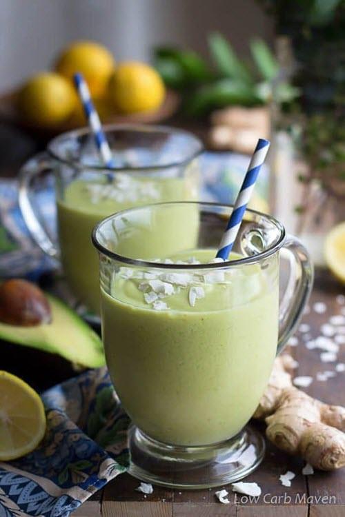 Two green smoothies in glasses, with avocado, ginger and lemon on the table. 