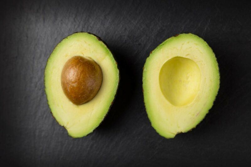 An avocado cut in half on a black background