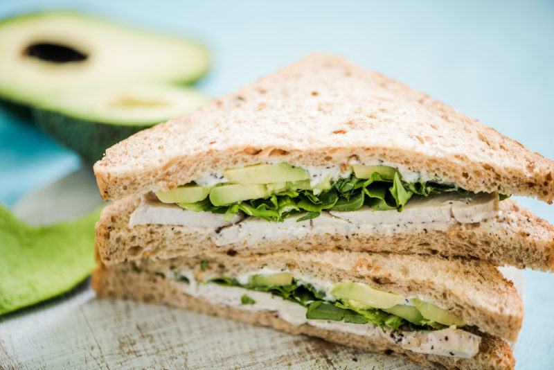 Sandwiches containing sliced avocados and greens