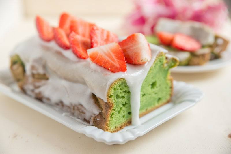 An avocado pound cake with white icing and strawberries