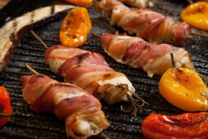 Bacon wrapped meat for the bbq | Food For Net Meat on a BBQ grill that has been wrapped in bacon next to some peppers