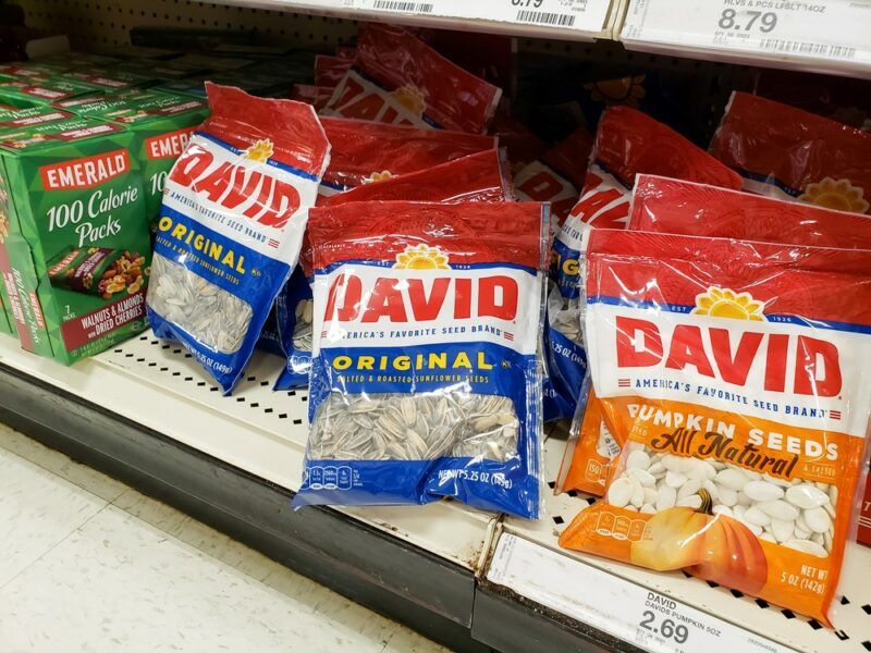 Bags of sunflower seeds, pumpkin seeds, and a box of almond bags on the shelf at a grocery store