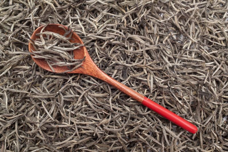 overhead shot of a pile of Baihao Yinzhen tea with a wooden ladle resting on top