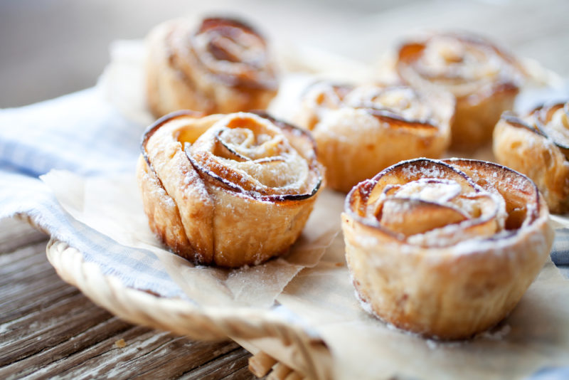 Six baked apple roses on a wooden table