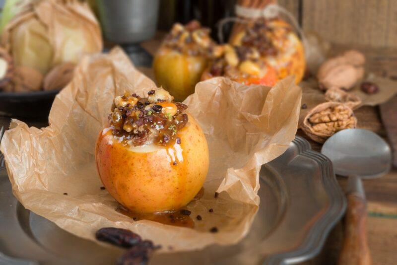 Baked apples on parchment paper, each with a delicious oat filling