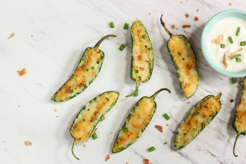 A flat lay image of seven jalapeno poppers sliced in half next to dipping sauce