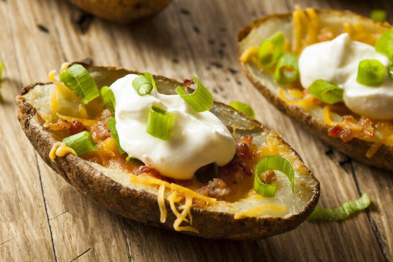 Two halves of a baked potato with sour cream, chives, and cheese