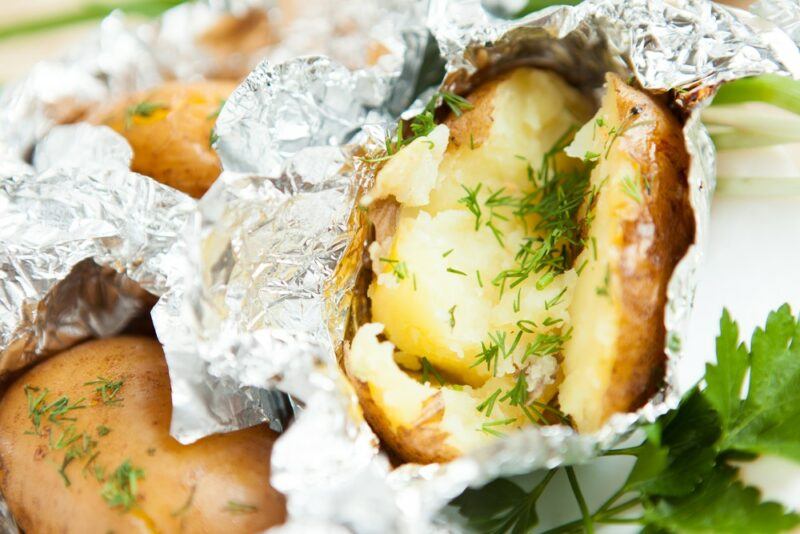 Baked potatoes in foil that have been opened to show the cooked potato