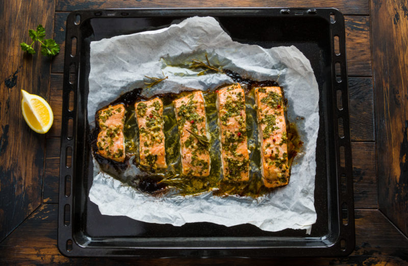 Parchment paper with baked salmon that has been covered in herbs