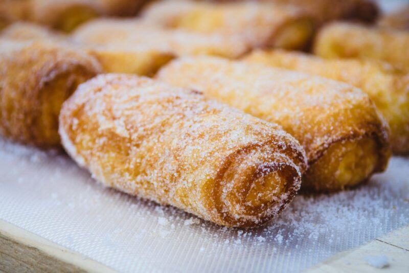 A selection of baked xuixo treats covered in sugar on some type of tray