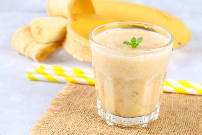 A Banana Cream Cocktail with bananas in the background