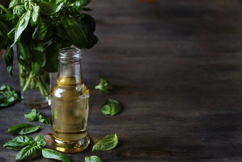 A bottle of simple syrup infused with basil, with basil leaves in the background