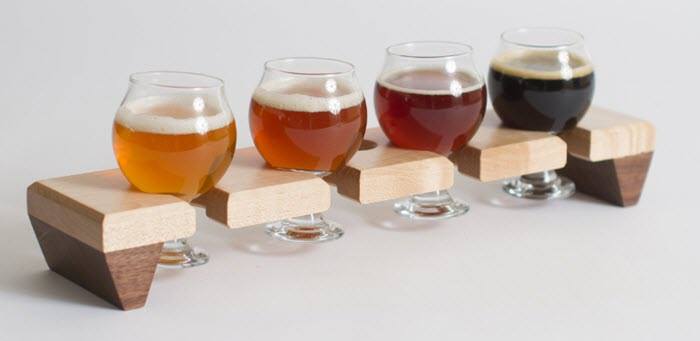 Two-toned wooden flight with four different colored glasses of beer. 