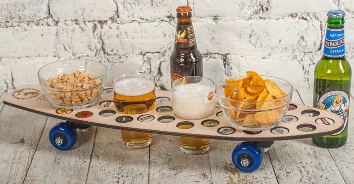 A skateboard-shaped beer flight with snacks and bottles of beer. 